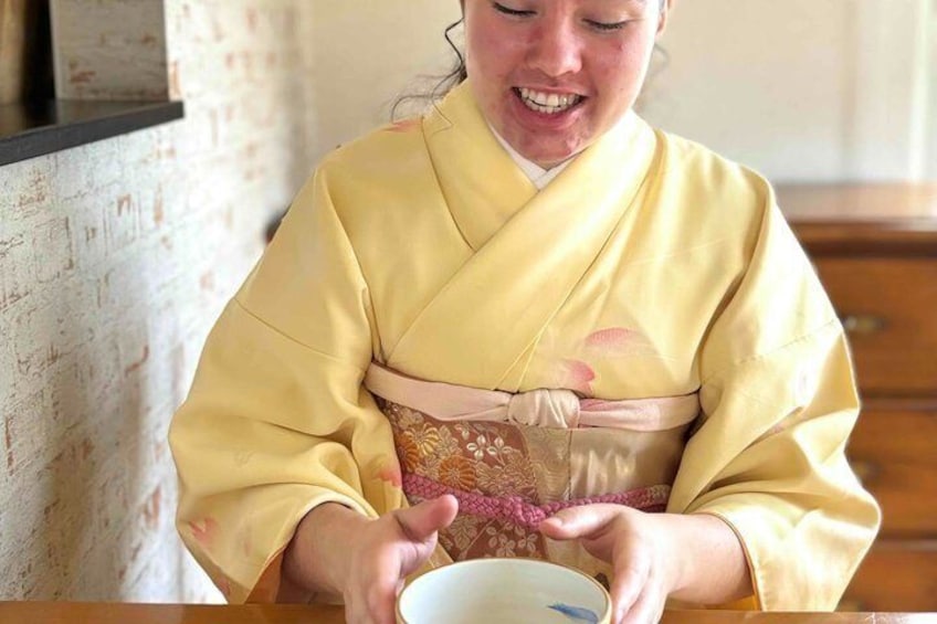 A person in traditional attire holding a bowl. 5