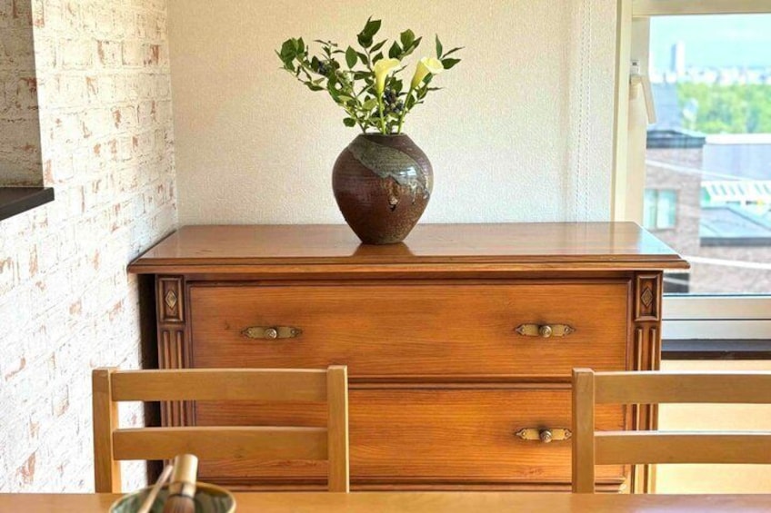 A wooden dresser with a vase of green leaves. 2