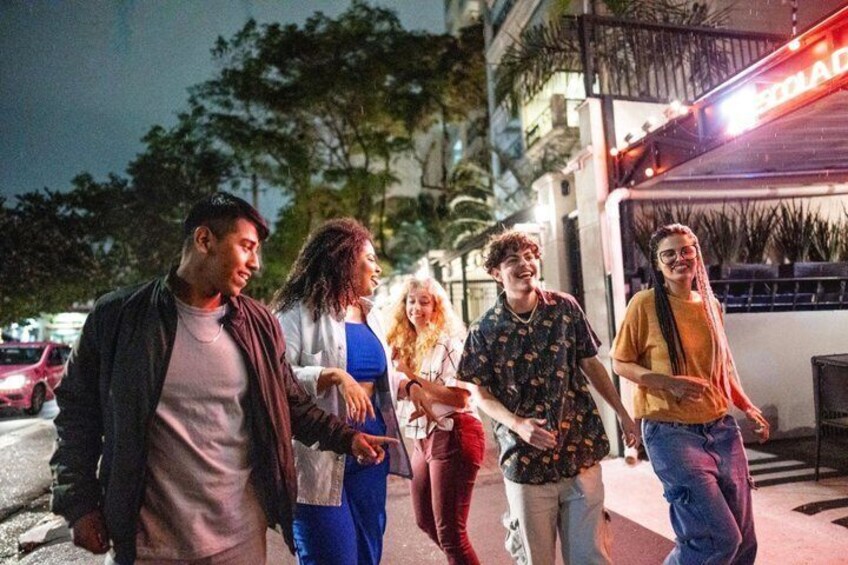 A group of people walking on a sidewalk at night. 3