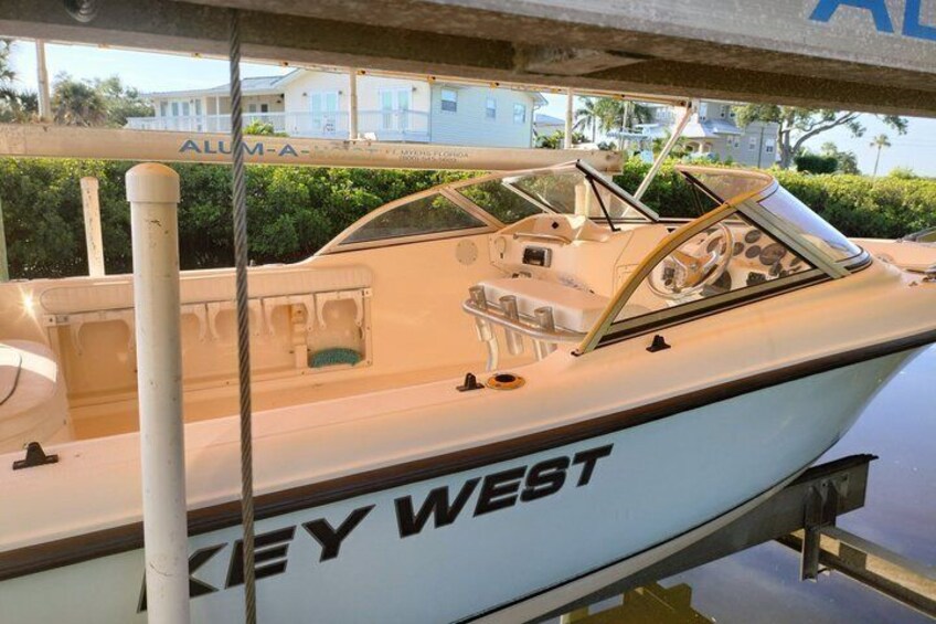 A boat named 'KEY WEST' docked at a marina with a clear view of the surrounding greenery and buildings in the background. 3