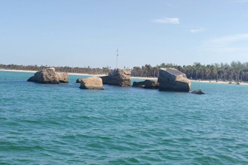 A calm sea with large rocks and a clear sky. 1