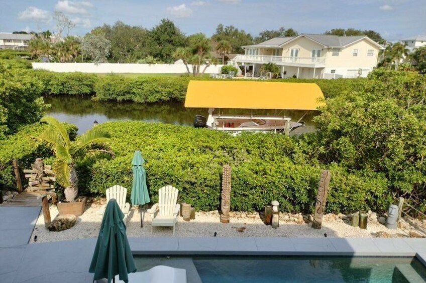 A swimming pool, white chairs, a green umbrella, and a yellow-roofed building. 2