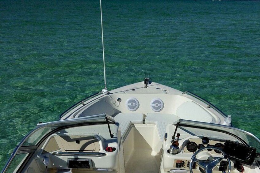 A boat's interior with a steering wheel, control panel, and a clear view of the water. 4