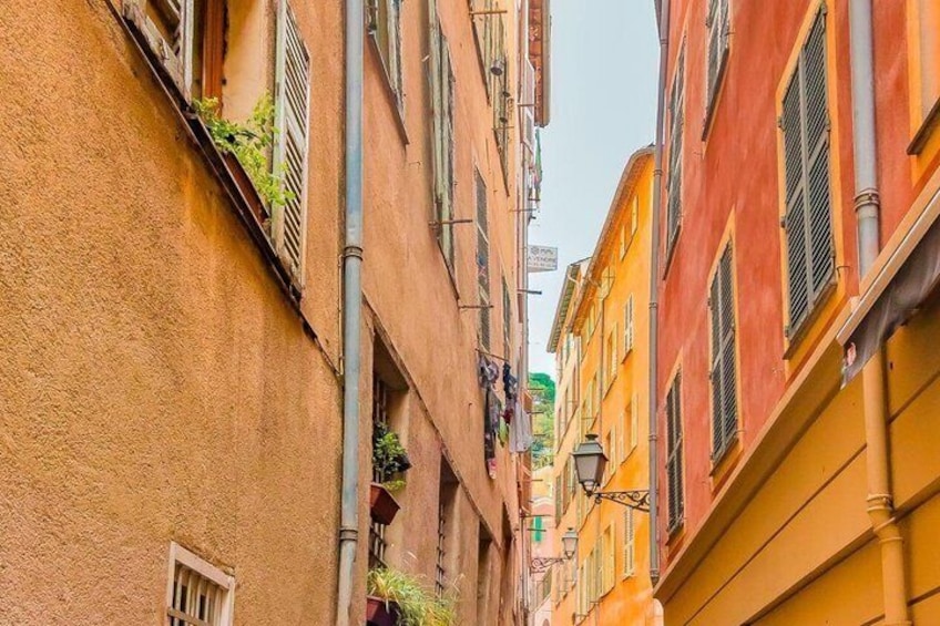 A narrow street with buildings painted in warm tones, a street lamp, and a visible sign. 2
