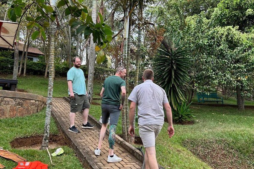 Three people walking on a brick pathway in a park with trees and grass. 4