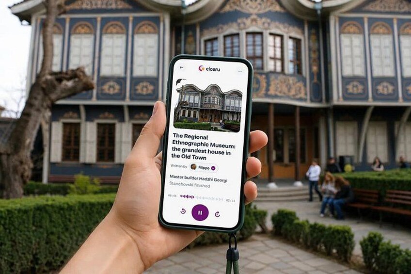 A hand holding a smartphone displaying a museum building. 1
