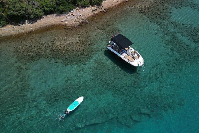 A boat anchored near a rocky shoreline with clear turquoise water. 1