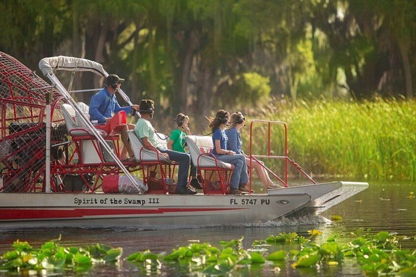 A boat with people on it, surrounded by water and greenery. 1