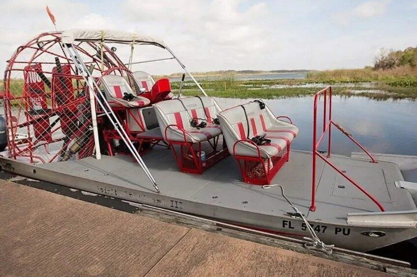 A boat with a canopy and seating, docked at a calm body of water. 3