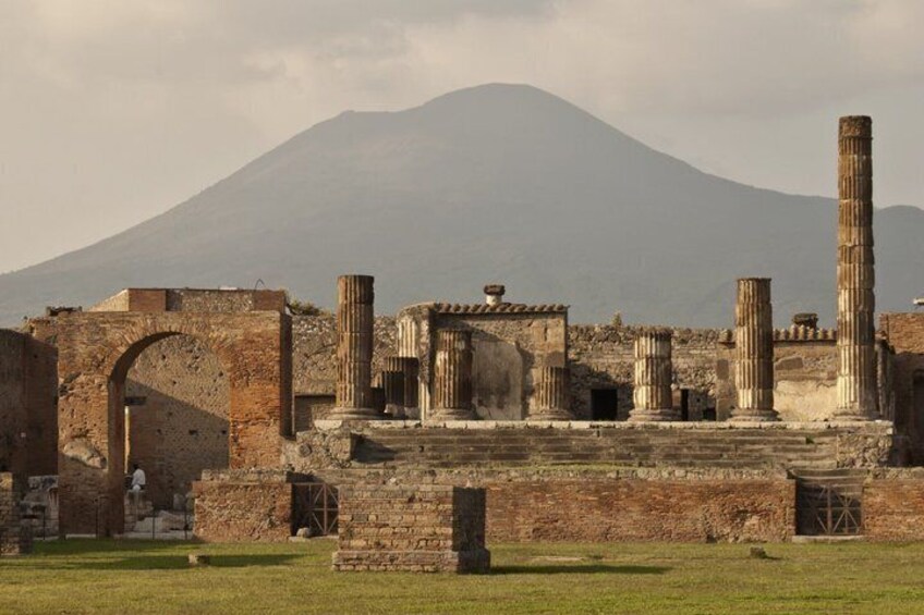 Ancient ruins with columns and an archway, set against a backdrop of a mountain. 2