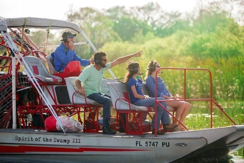 A boat with people on board, a red railing, and a water body in the background. 1