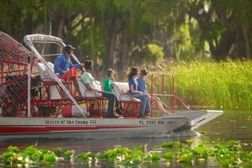 A boat with people on it, surrounded by water and greenery. 4