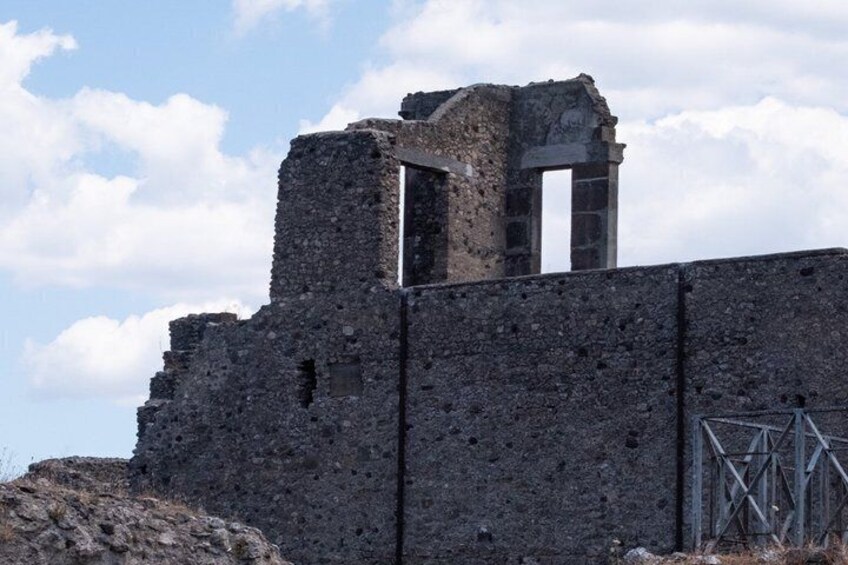A ruined stone structure with a doorway and a metal gate. 3