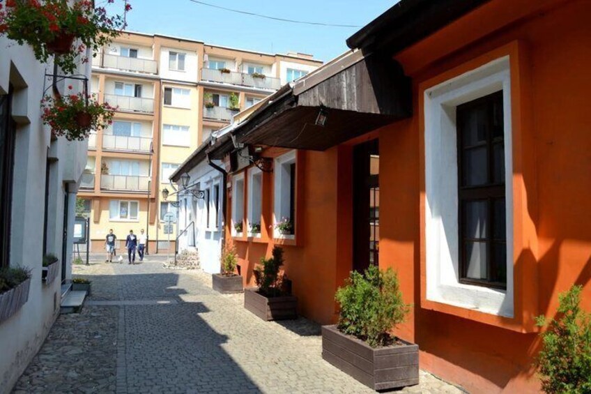 A cobblestone street lined with orange buildings, a clear sky, and a few pedestrians in the distance. 4