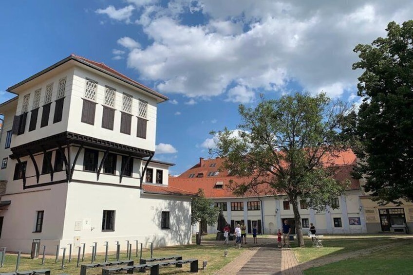 A building with a white facade and dark trim, a tree in the foreground, and a clear blue sky. 3