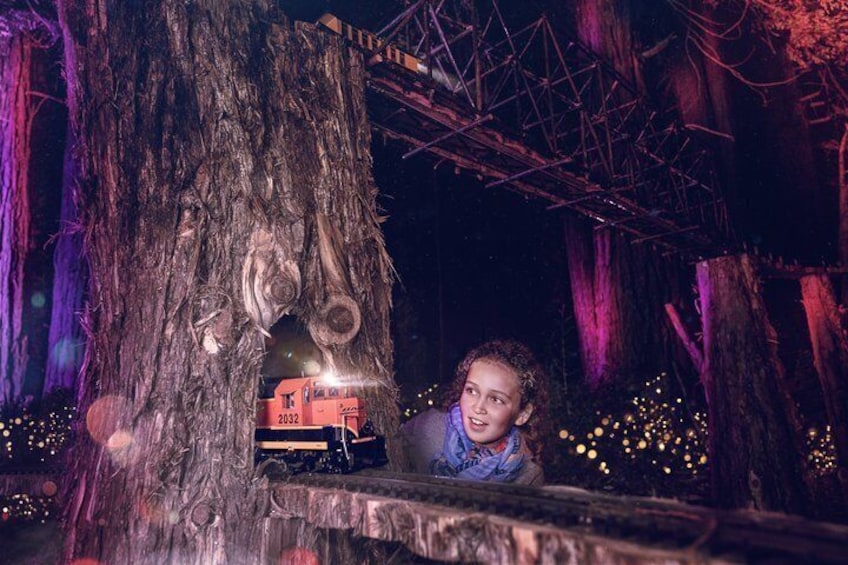 A child near a tree with a toy train on a platform. 3