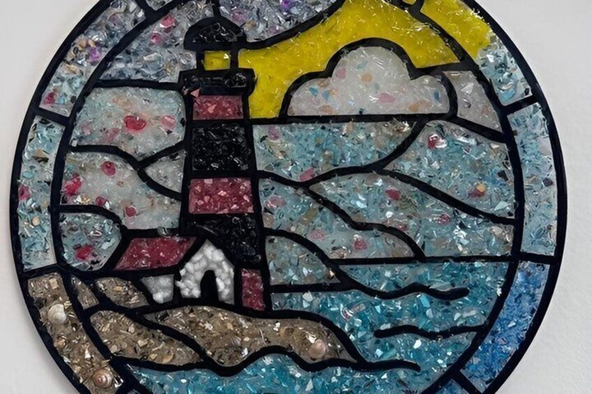 A stained glass artwork with a lighthouse, waves, and a sun. 5