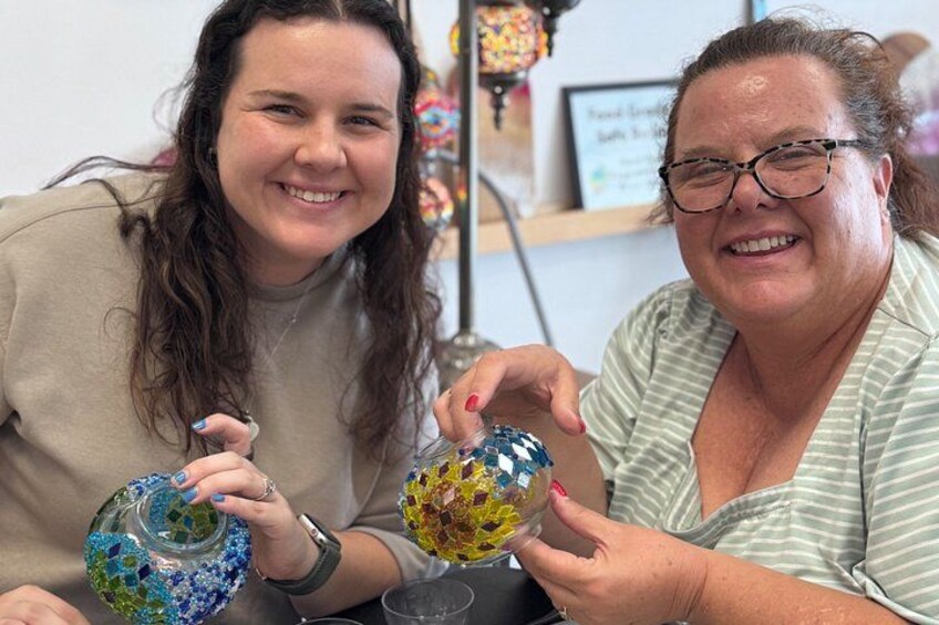Two people holding colorful glass containers. 2