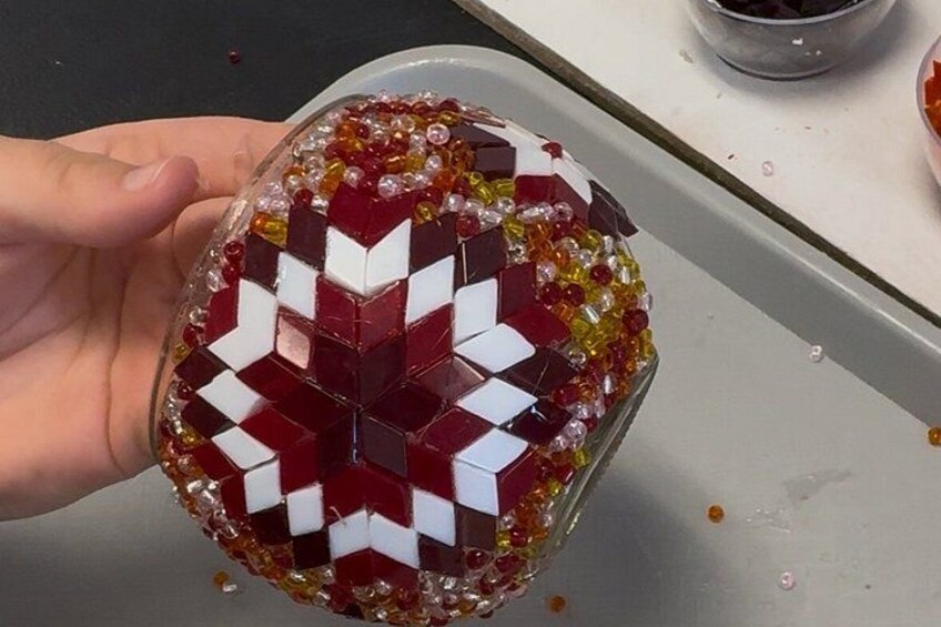 A hand holding a beaded object with a geometric pattern. 5