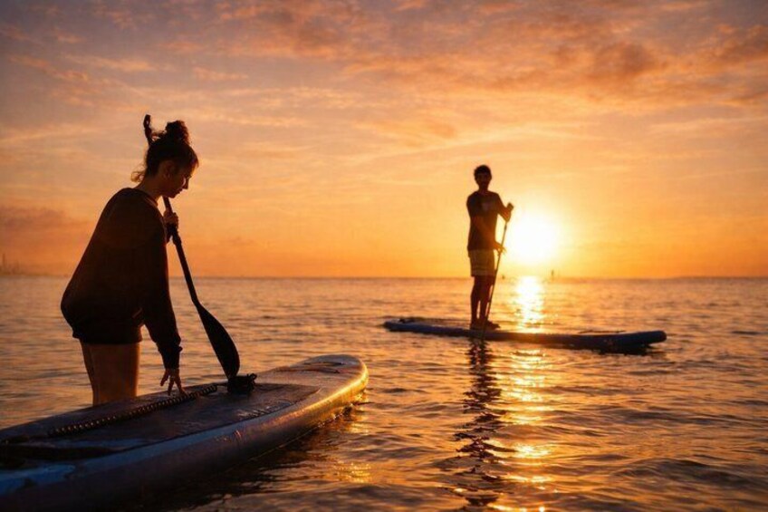 Two people paddleboarding on a calm sea during sunset. 2