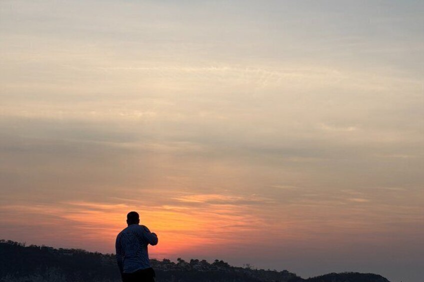 A person standing on a hill overlooking a sunset. 3