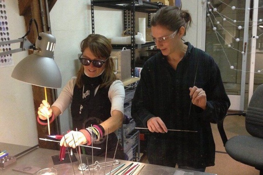 Two people working with wires and tools at a table in an indoor setting. 4