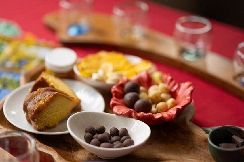 A table with various food items including a slice of cake, bowls of nuts, and a plate of macarons. 2