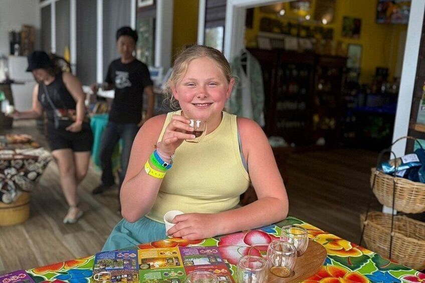 A person sitting at a table with a colorful tablecloth, holding a glass. 5