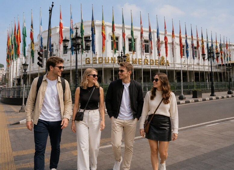 Four people walking in front of a building with multiple flags. 4