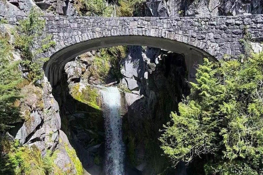 A stone bridge over a waterfall with surrounding greenery. 5
