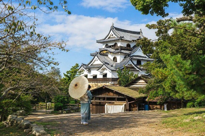 A traditional Japanese castle with a person holding a fan in front. 2
