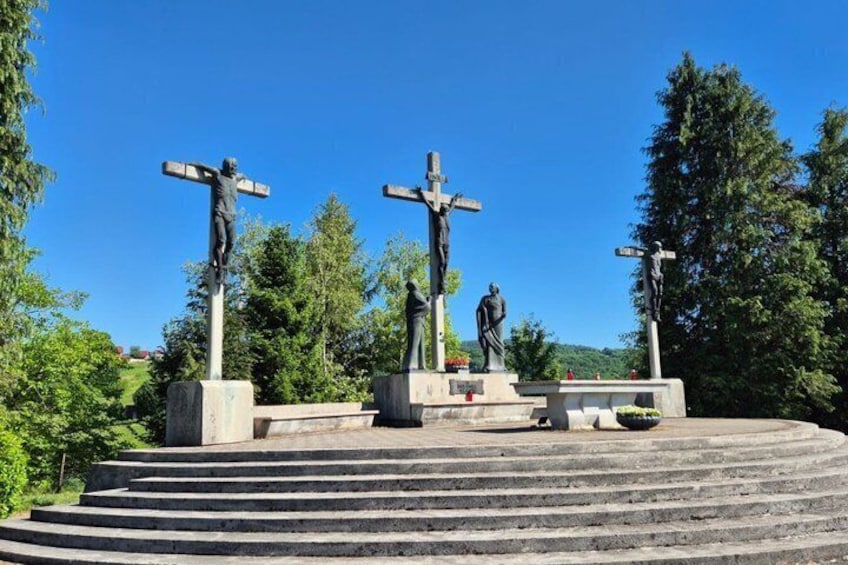 A cross with a figure, a statue, and a cross on a platform with steps. 5