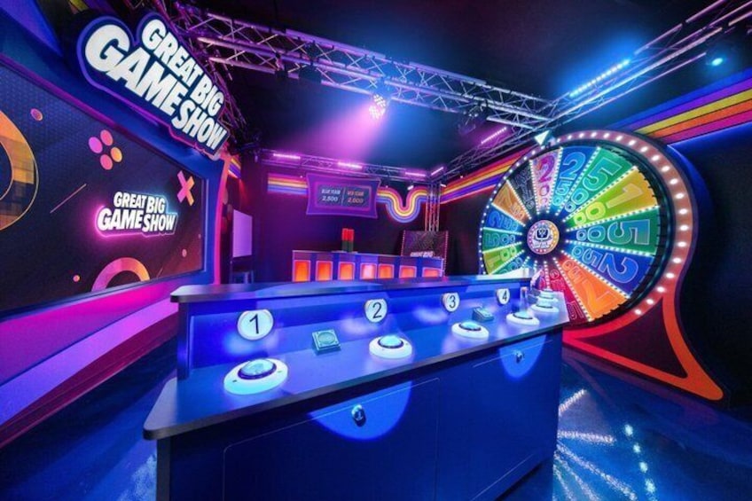 A game show set with a spinning wheel, podium, and neon signage. 5