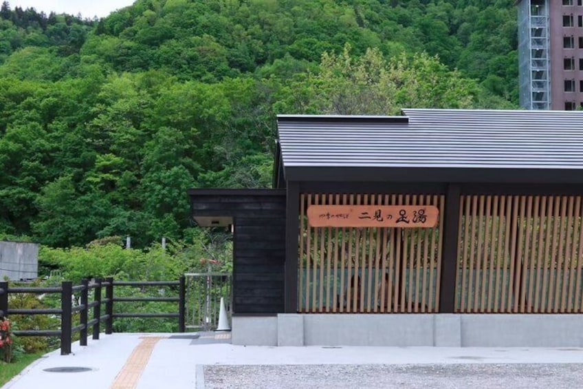 A building with a sign in a foreign language, surrounded by greenery and a fence. 4