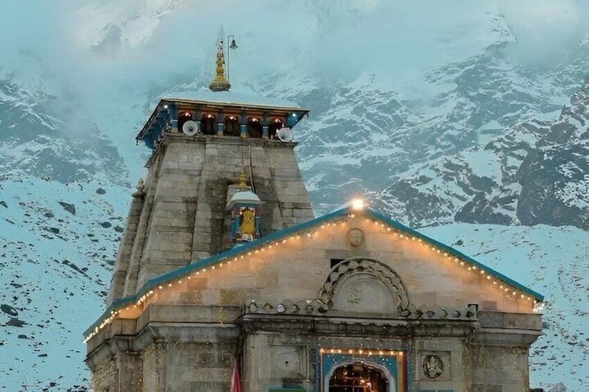 A stone building with a pointed roof, surrounded by snow-covered mountains. 1