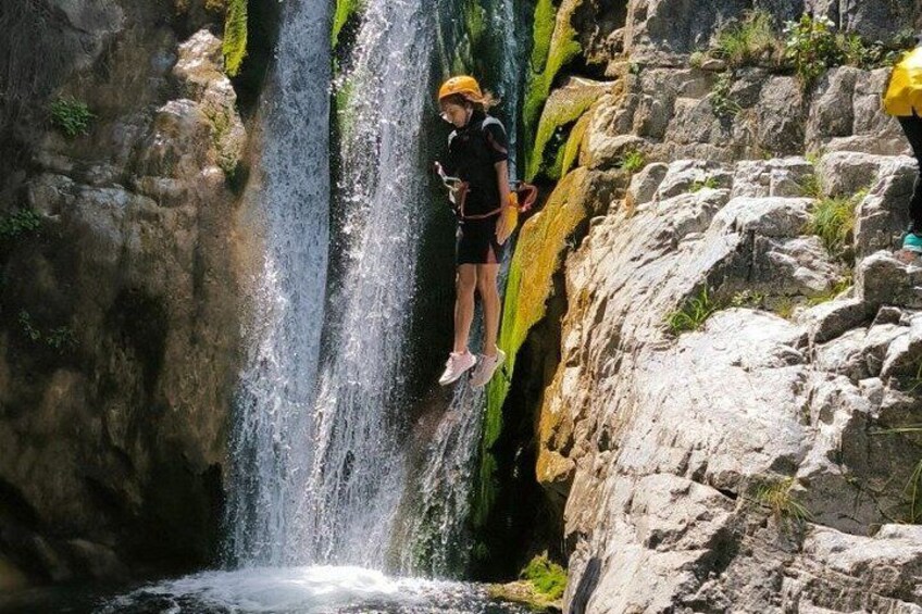 A person standing on a rock ledge above a waterfall. 2