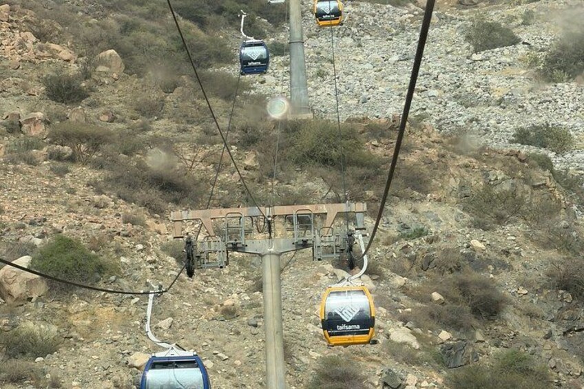 A cable car system in a mountainous area with rocky terrain and sparse vegetation. 3