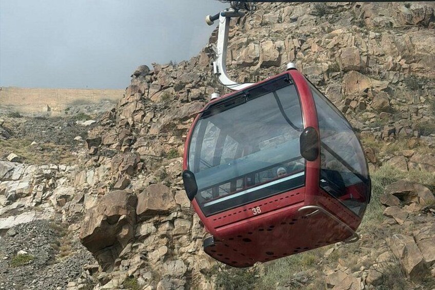 A red cable car suspended over rocky terrain. 5