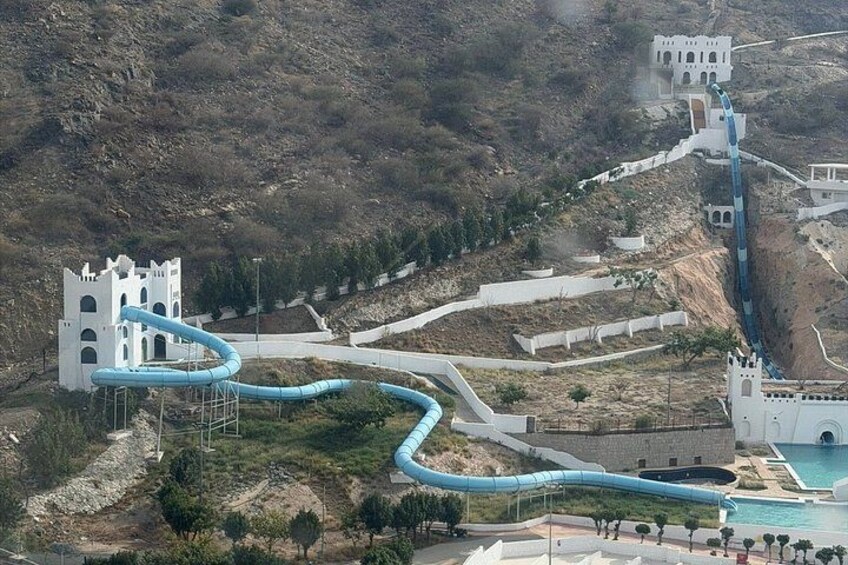 A water park with a castle-like structure, winding water slides, and a pool. 4