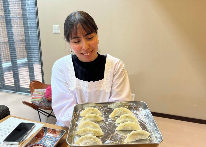 A person holding a tray of dumplings. 3