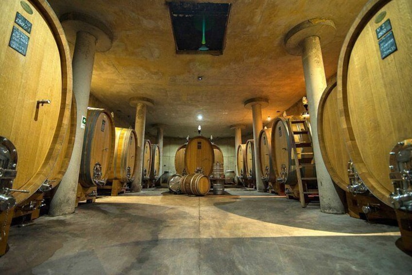 A cellar with wooden barrels, columns, and a central staircase. 3