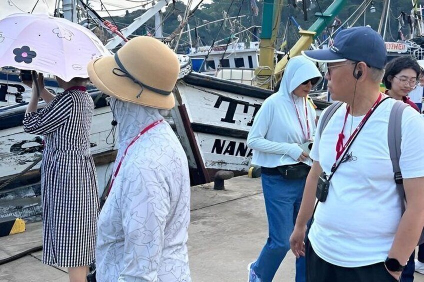 People standing near boats with a sign that reads 'NANA'. 5