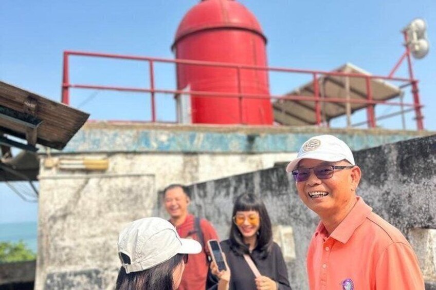 A lighthouse with a red tower, a person in a white cap, and another in a red shirt. 1