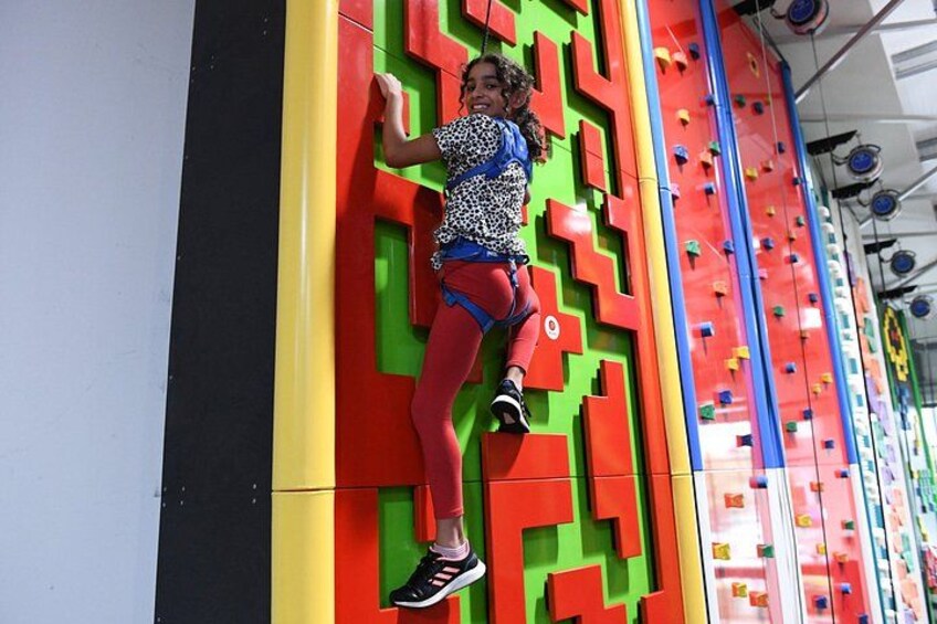 A person climbing a colorful wall with geometric patterns. 5