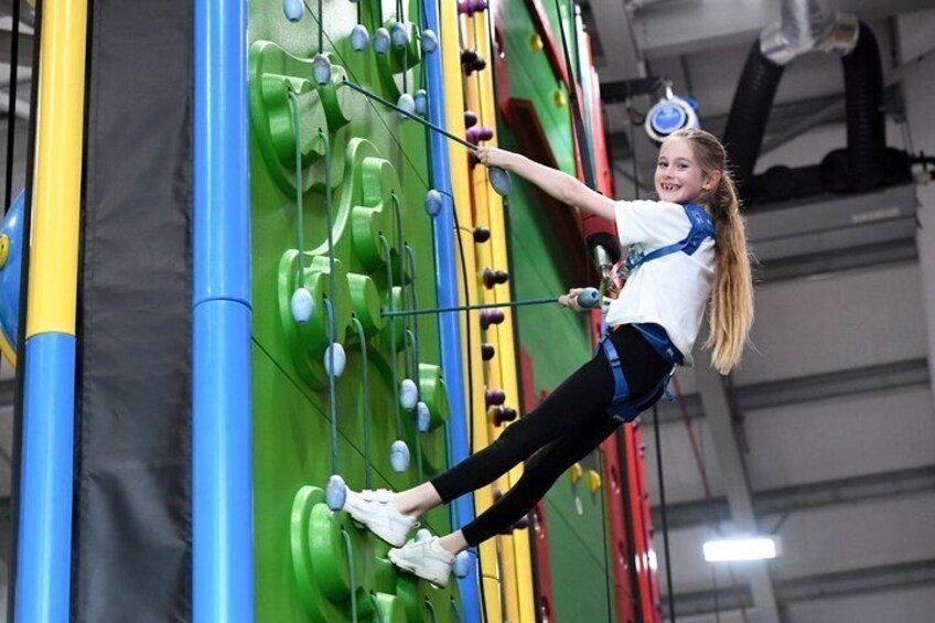A person climbing a colorful indoor climbing wall. 3