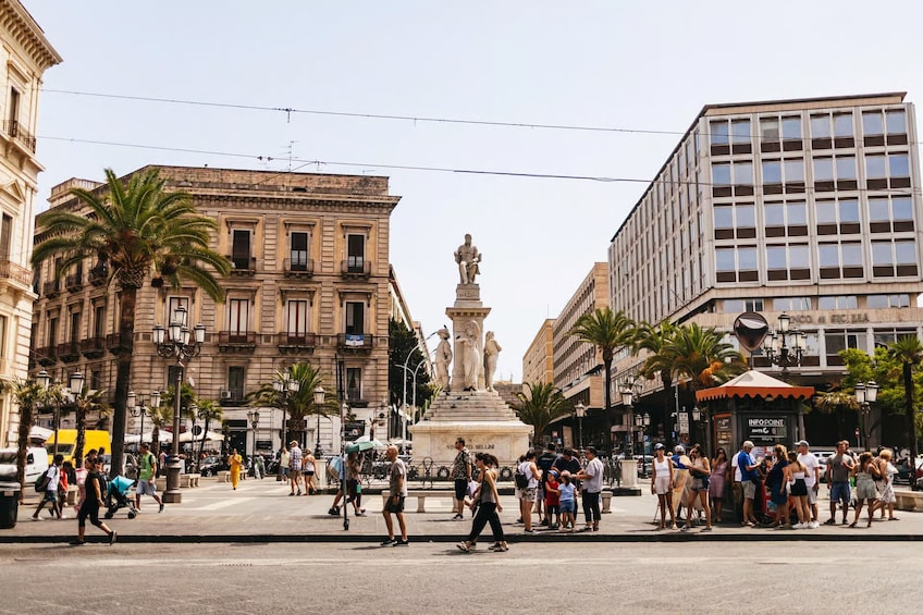 A busy urban square with a central monument, palm trees, and historic buildings. 4