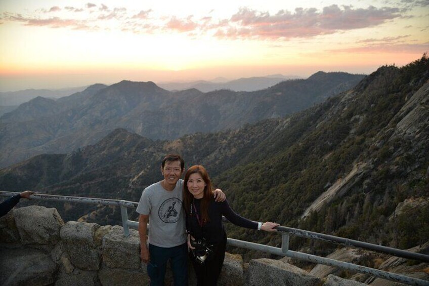 A couple standing on a rocky ledge with a mountainous landscape in the background. 5