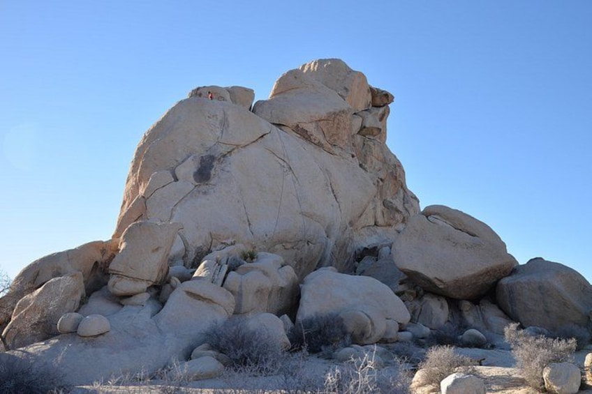 A large rock formation with multiple layers and a clear blue sky. 3