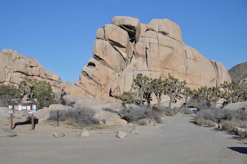 A desert landscape with large rock formations, sparse vegetation, and a paved road. 5