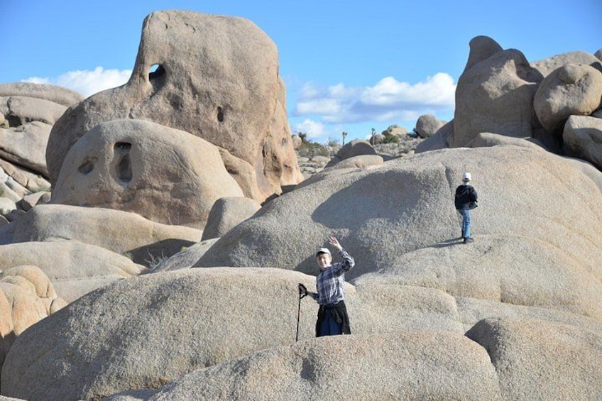 Two people hiking on large boulders in a desert landscape. 2